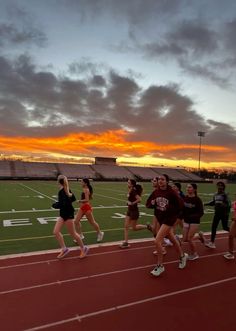 a group of people running on a track at sunset