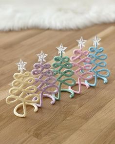 three crocheted christmas tree ornaments on a wood floor