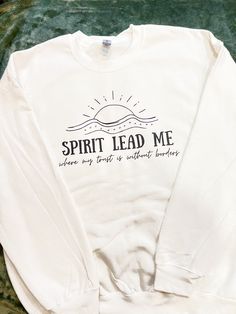 a white sweatshirt with the words spirit lead me on it sitting on a green blanket