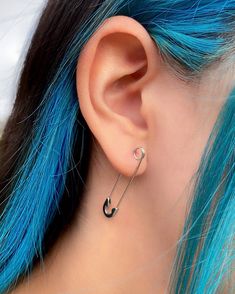 a woman with blue hair and piercings wearing an ear cuff in front of her ear