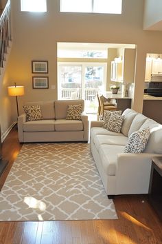 a living room with two couches and a rug on the floor in front of a fireplace