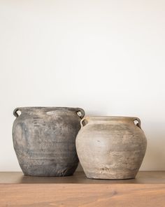 two vases sitting on top of a wooden shelf