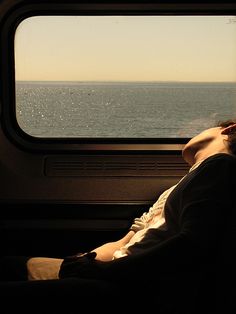 a person sitting on a train looking out the window at the water and land below