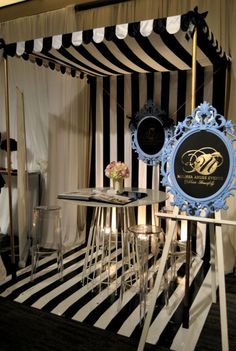 a black and white striped room with an awning over the table, two stools in front of it