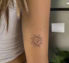 a woman's arm with a small sun tattoo on the left side of her arm