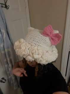 a woman wearing a crocheted hat with a pink bow