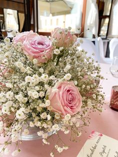 pink roses and baby's breath in a vase on a table at a wedding