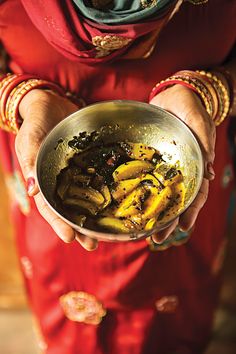 a woman holding a metal bowl filled with food