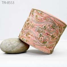 a pink and gold cuff bracelet sitting on top of a rock next to a stone