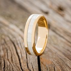 the wedding ring is made from yellow gold and white ceramic, with a rounded edge