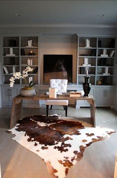 a living room filled with furniture and a cow hide rug