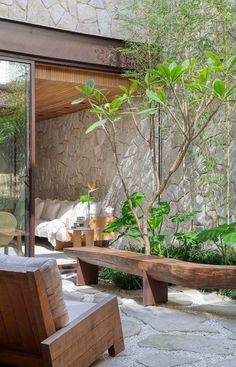 a wooden bench sitting in front of a stone wall next to a green planter