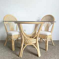 a glass table with two chairs next to it on carpeted flooring in front of a white wall