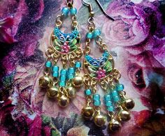 "These Small Floral belly dancer Chandelier Earrings are made with hand-painted plated floral pendants adorned with colorful glass beads and dangling jingle bell charms. Available with French Wires, Leverbacks, Posts or Clip-Ons. -2 1/2\" Long x 1\" Wide -0.1 oz. ea -Many Colors Available in the pull-down menu! (Periwinkle is seen in the video) Metal Finishes Available: -Gold -Silver Longer Version: https://www.etsy.com/listing/251271742/ready-to-ship-silver-gypsy-bellydancer?ref=shop_home_activ Bohemian Festival Earrings With Bells, Bohemian Bell Earrings For Festivals, Festive Bohemian Chandelier Earrings With Dangling Beads, Traditional Blue Chandelier Earrings For Festivals, Blue Traditional Chandelier Earrings For Festivals, Blue Chandelier Earrings For Festivals, Festive Bohemian Dangle Chandelier Earrings, Handmade Blue Chandelier Earrings For Festive Occasion, Blue Latkans Chandelier Earrings For Festivals