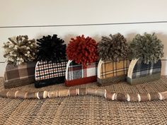 four plaid vases with pom - poms are lined up against a wall