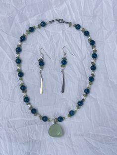 This set is handmade with salvaged materials. The blue and green beads are made of glass, the white beads are small freshwater pearls, and the pendant is a green stone, giving the necklace a satisfying weight without being too heavy. The hardware is sterling silver plated.  Necklace length: 16 inches  Earring length: 2.5 inches Green Beaded Necklace With Pearl Drop For Gift, Green Czech Glass Beaded Necklace With Dangling Beads, Pearl Beaded Necklace, Green Pendant, Green Pendants, Green Beads, Green Bead, White Beads, Green Stone