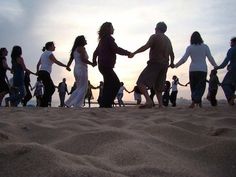 a group of people holding hands on the beach