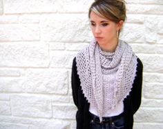 a woman standing in front of a brick wall wearing a white scarf and black cardigan