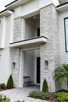 the front entrance to a modern home with white siding and stonework on the exterior