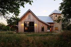 a large wooden house sitting on top of a lush green field next to tall grass