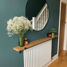 a vase filled with flowers sitting on top of a wooden shelf next to a radiator