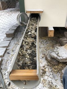 a long metal pipe with rocks and wood in the bottom is being used as a drainage system