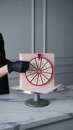 a woman in black gloves is cutting a cake with a red and white wheel on it