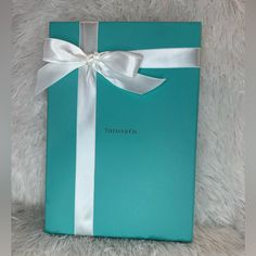 a blue gift box with a white ribbon and bow sitting on top of a furry surface