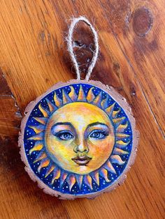 a sun painted on a piece of wood with string hanging from it's end