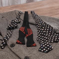 several ties laid out on top of a gray sweater with polka dots and black buttons