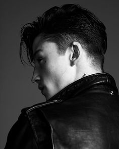 black and white photograph of a man wearing a leather jacket with ear piercings on his ears