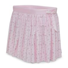 a pink crib bed skirt with flowers and bows on the bottom, in front of a white background