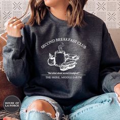 a woman sitting on a couch wearing a sweatshirt that reads second breakfast club the shine, middle earth