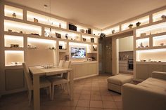 a living room filled with white furniture and lots of built - in shelving units