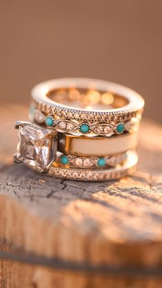 two wedding rings with turquoise stones and diamonds on top of a piece of drift wood