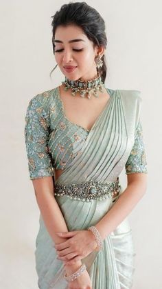 a woman in a green sari with jewelry on her neck and hands behind her back