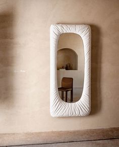 a mirror hanging on the wall next to a chair