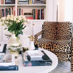 a leopard print chair sitting next to a vase with flowers in it on top of a table