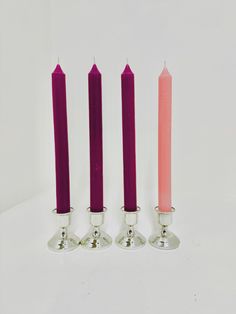 three candles are sitting next to each other on a white surface with one pink candle in the middle