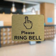 a sign that says please ring bell in front of a room with tables and chairs