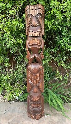 an old wooden carved totema sitting in front of some bushes