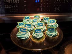 cupcakes with blue frosting sitting on a plate in front of an oven