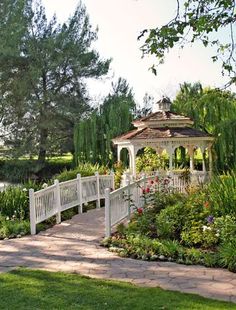 a white gazebo sitting in the middle of a lush green park