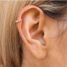 a woman's ear is shown with a single diamond in the middle