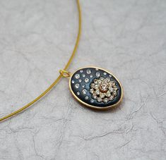 a black and gold necklace with a flower in the center on a white surface,