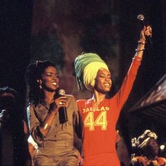 two women singing into microphones while standing next to each other in front of a crowd