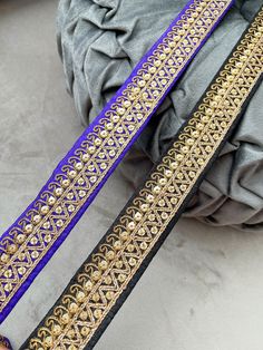 two purple and gold belts sitting on top of a gray cloth covered bag next to each other