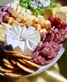 an assortment of cheeses, meats and crackers on a plate