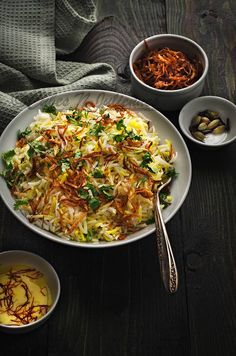 a white bowl filled with coleslaw next to two bowls of other food on a table