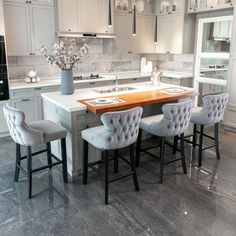 a kitchen with white cabinets and gray chairs